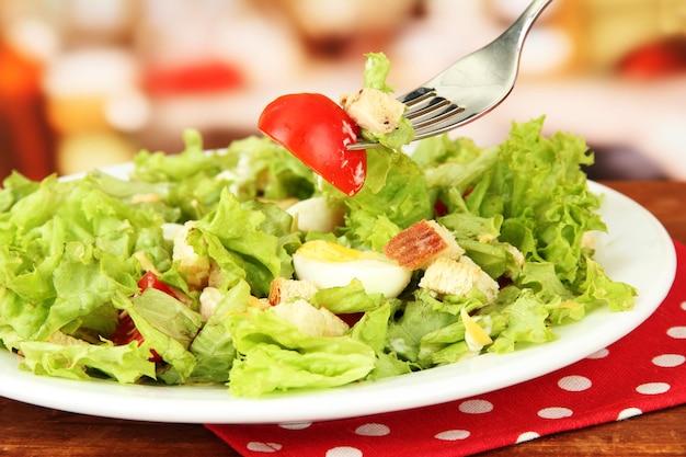 Caesar salad on white plate on bright background