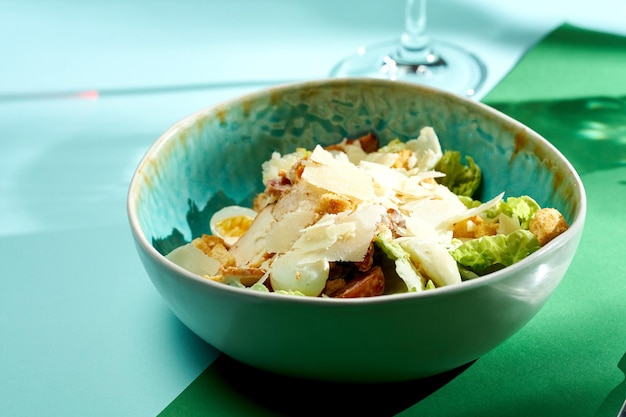 Caesar salad with chicken, croutons and parmesan. Bright backgrounds. Hard shadows, selective focus.