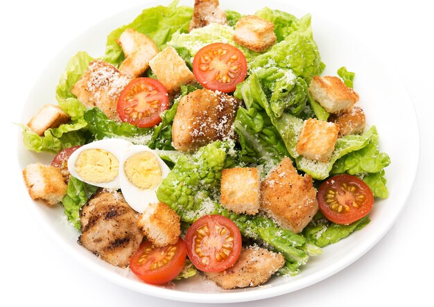 Caesar salad with chicken, croutons and parmesan in a plate isolated on a white background, close-up