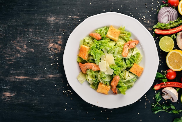 Caesar salad with chicken and fresh vegetables On a wooden background Top view Copy space