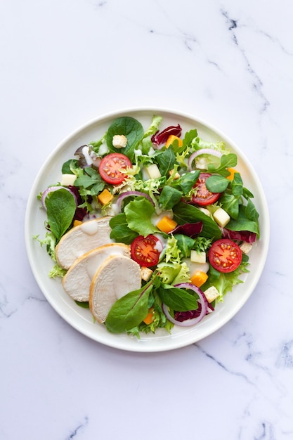 Foto insalata caesar con lattuga di pollo pomodoro formaggio e salsa su sfondo bianco