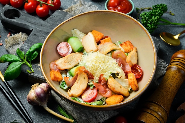 Caesar salad with chicken and vegetables On a plate Restaurant serving Close up On a dark stone background