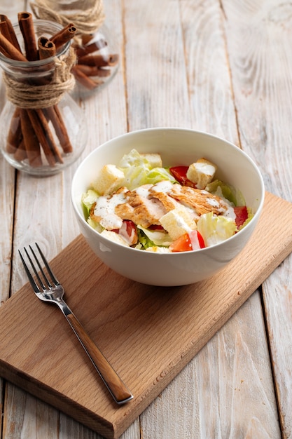 Caesar salad with chicken on the wooden board