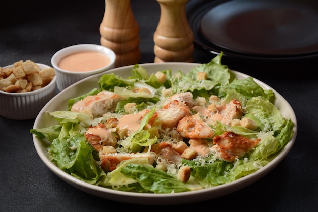 Caesar Salad with grilled chicken, Cheese and Croutons with lettuce, on plate.  Grilled chicken breasts and fresh vegetables in plate.