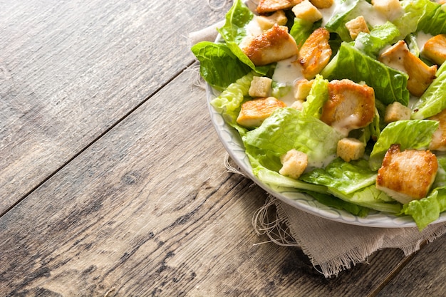 Caesar salad with lettuce,chicken and croutons on wooden table