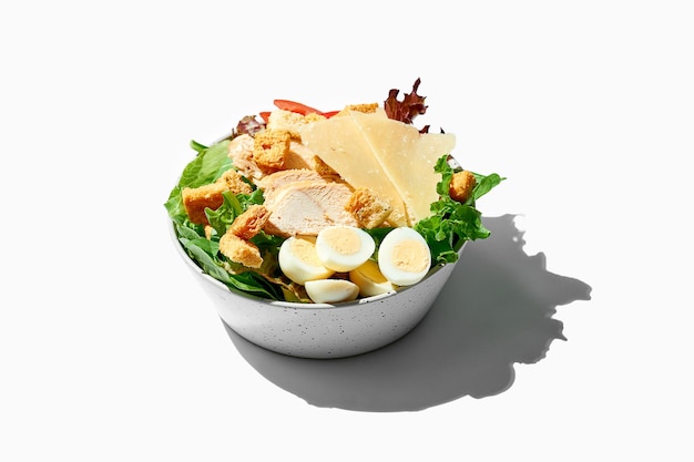 Caesar salad with parmesan and chicken in a bowl on a white background