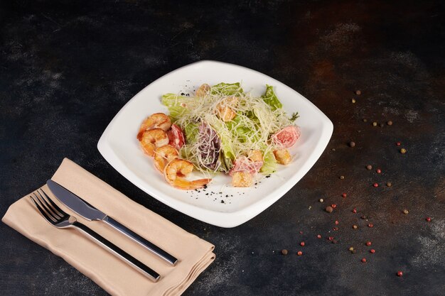 Caesar salad with seafood and shrimp, background dark