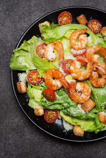 Photo caesar salad with shrimp, croutons and parmesan, top view