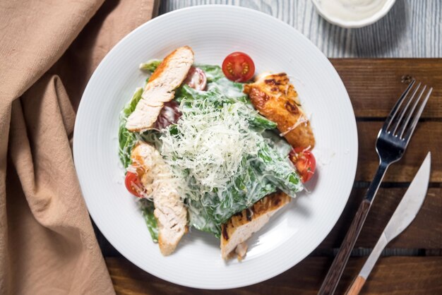 Photo caesar salad with turkey roasted breast meat cherry tomatoes shredded parmesan cheese salad dressing