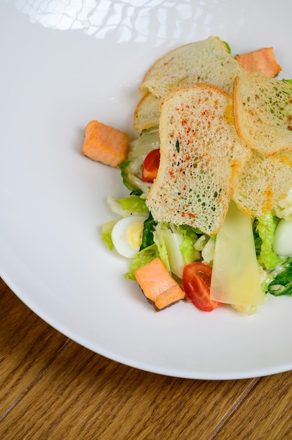 Caesar salade met zalm op witte plaat op houten achtergrond.caesar salade met zalm, bovenaanzicht