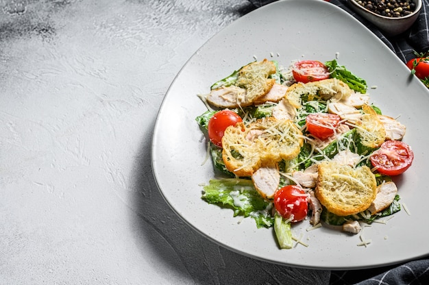 Caesarsalade met gegrilde kip, croutons, kwarteleitjes en kerstomaatjes. Witte achtergrond.