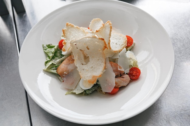 Foto caesarsalade met geroosterde kipfilet croutons, kerstomaatjes en parmezaanse kaas op witte plaat