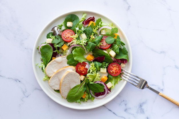 Foto caesarsalade met kippensla, tomatenkaas en saus op witte achtergrond