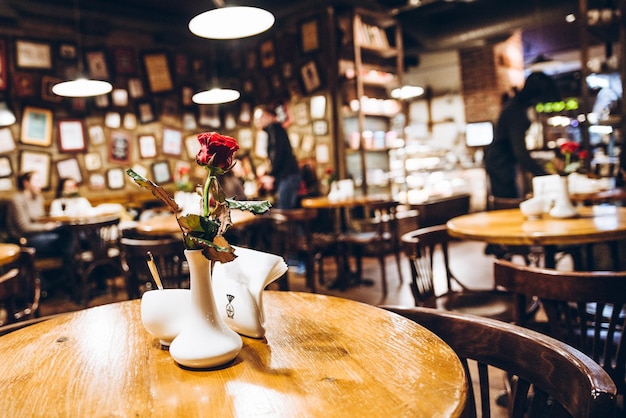 Cafe binnen lege tafel met rode roos in vaas