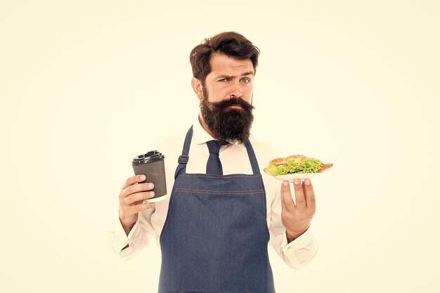 Cafe food concept man bearded waiter wear apron carry plate with food and coffee cup delicious croissant enjoy your meal guy serving croissant stuffed lettuce and fresh vegetables healthy food