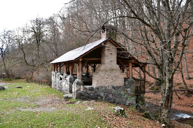 Cafe in the mountains. A cafe with a large stone oven under a wooden roof. Cafe on the bank of a mountain stream.