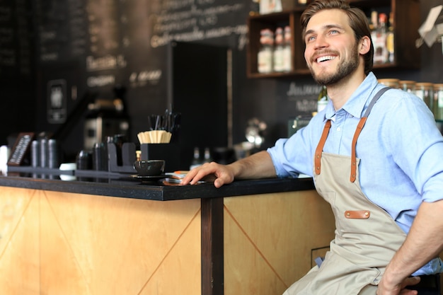 Cafe owner. Pleasant delighted man sitting near the counter, smiling.