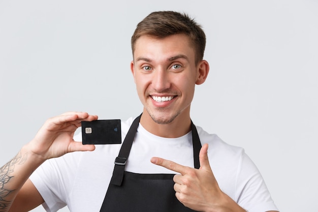 Cafe and restaurants, coffee shop owners and retail concept. Close-up shot of handsome salesman, store employee showing credit card, advertising banking system or contactless payment