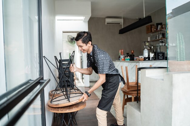 Cafe serveerster glimlach bij het verhogen van een stoel