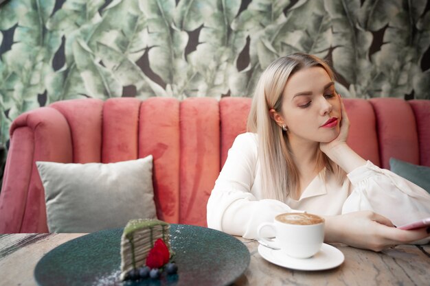 Cafe stad levensstijl vrouw op telefoon drinken koffie SMS-bericht op smartphone in trendy stedelijke café.