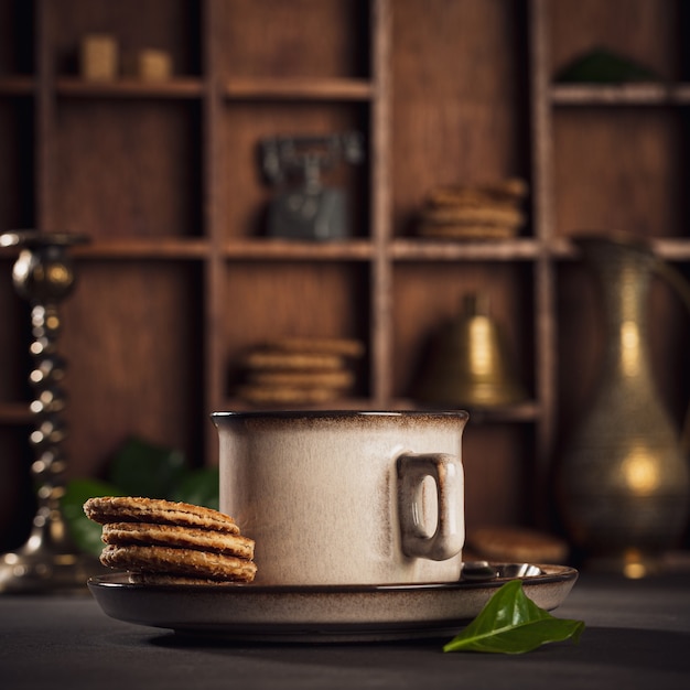 Cafe surface with brown cup of coffee and dutch traditional cookies stroopwafels. Retro style toned