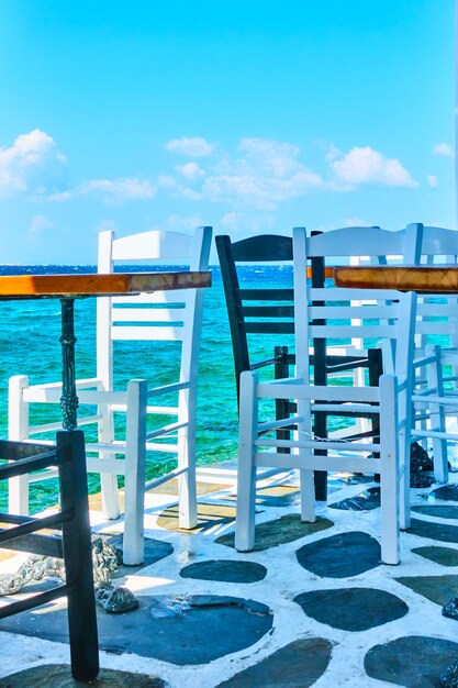 Cafe tables and chairs near water in Mykonos Island, Greece