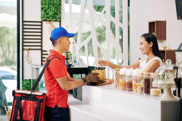 Photo cafe worker giving order to courier