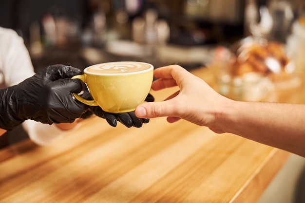 Cafébezoeker probeert de warme drank te bereiken