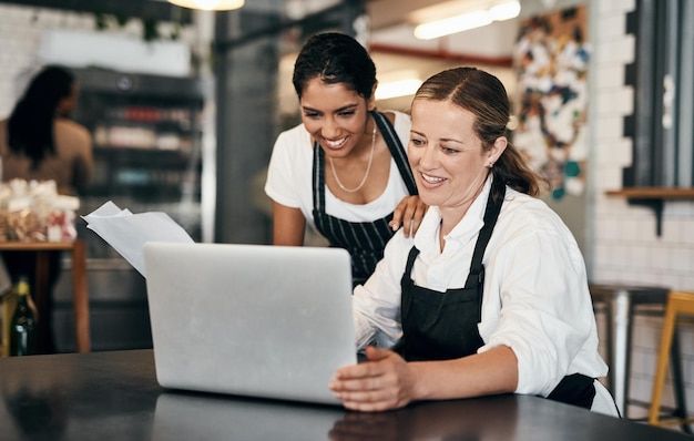 Cafémedewerkers die op een laptop werken terwijl ze online budgetstrategie plannen Gelukkige koffiemanager en collega die teamwerk leren in startende bedrijven winstverhoging en goede recensies op sociale media