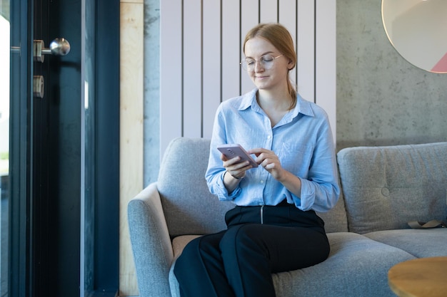 Caféstadsportret van gelukkige jonge kantoorassistent die op afstand online werkt met mobiele telefoon