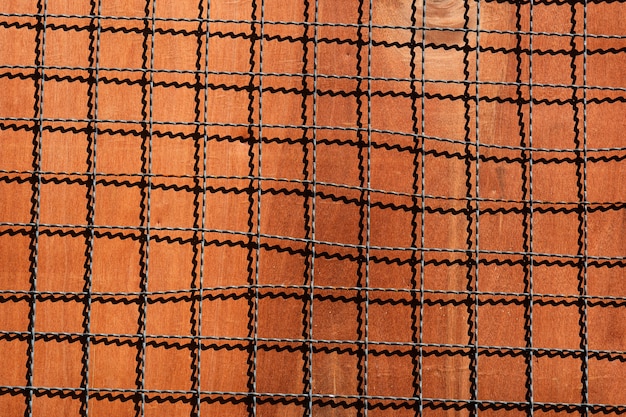 Cage metal net with shadow on brown wood plate