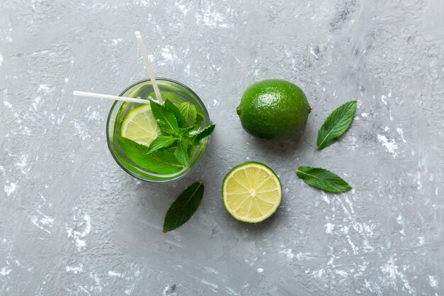 Caipirinha Mojito cocktail vodka or soda drink with lime mint and straw on table background Refreshing beverage with mint and lime in glass top view flat lay