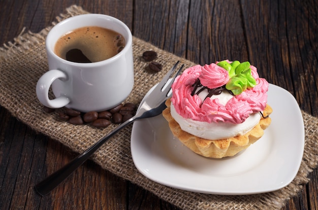 Cake and cup of hot coffee on dark wooden table