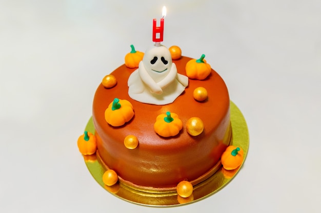 Cake decorated for halloween with pumpkins ghosts and a burning candle