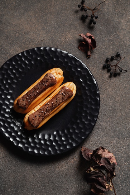 Cake eclair, eclairs op plaat, droge de herfstbladeren op donkere achtergrond