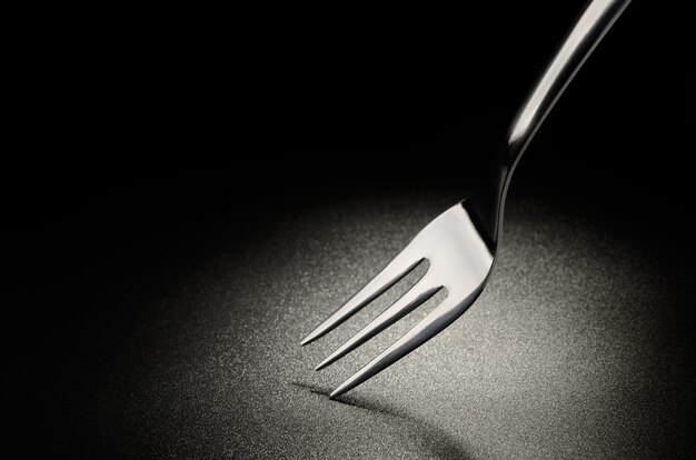 Cake fork on the black grained surface