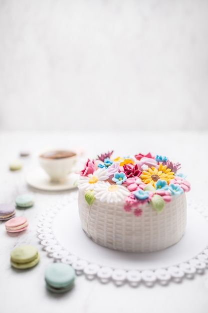 Cake from marzipan flowers macaroons and a cup of black coffee.