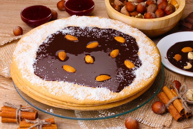 Cake on glass stand and nuts on wooden table