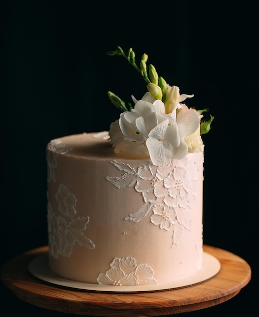 Cake is decorated with flowers on a dark background.