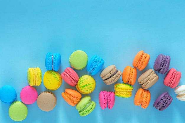 Cake macaron or macaroon on turquoise background from above, colorful almond cookies, pastel colors,