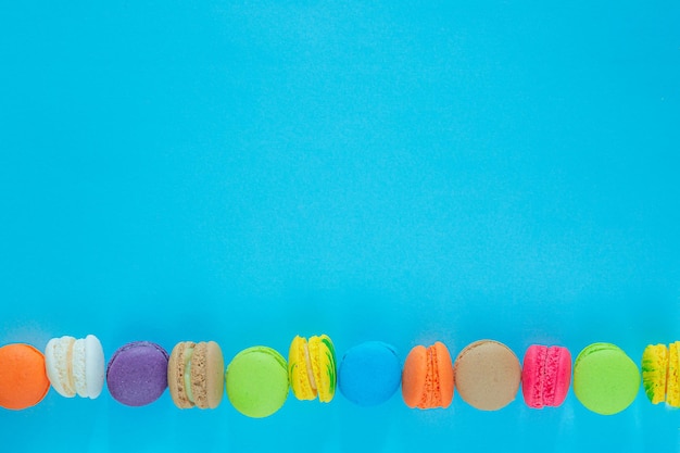 Фото Торт макарон или миндальное печенье на бирюзовом пастельном фоне сверху красочное миндальное печенье на десерт