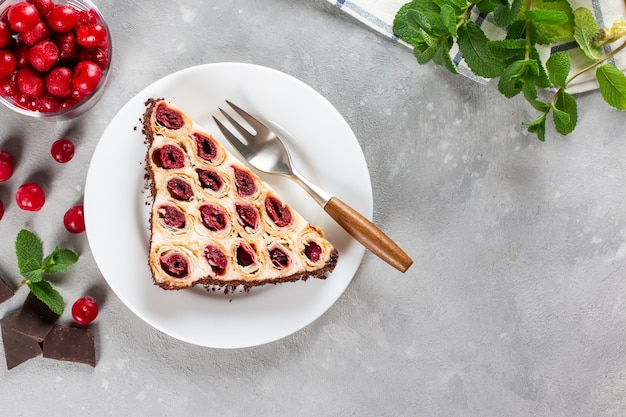 Cake met kersen, room en chocolade op een lichte achtergrond