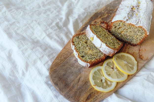 Foto cake met maanzaad en citroenschil, bestrooid met poedersuiker. cupcake met citroen op een houten bord.