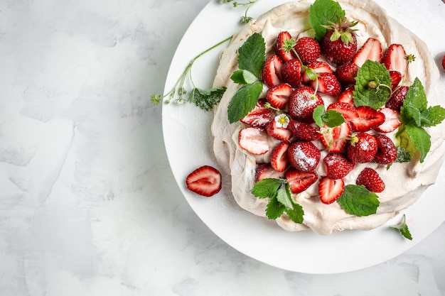 Cake Pavlova with whipped cream, fresh strawberries and mint