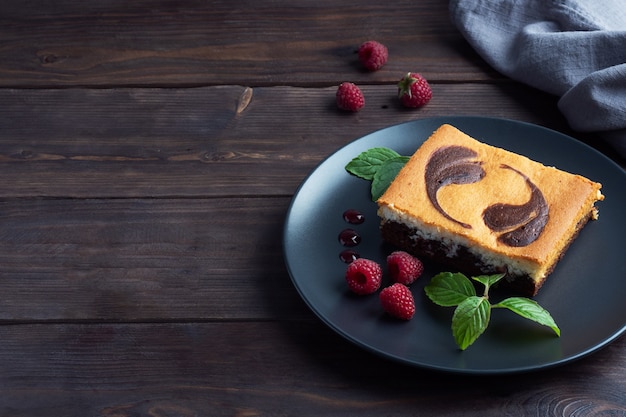 Торт на тарелке шоколадных пирожных и творожного чизкейка с малиной