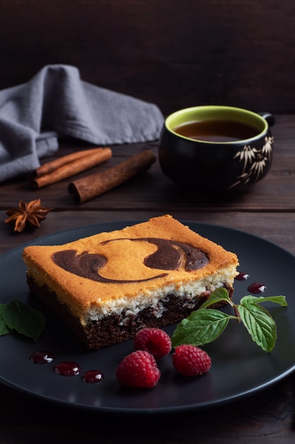 Torta su un piatto di brownie al cioccolato e cheesecake alla ricotta con lamponi