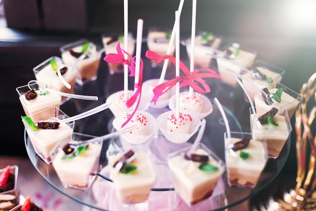 Cake pops and cupcakes on a transparent stand candy bar at wedd