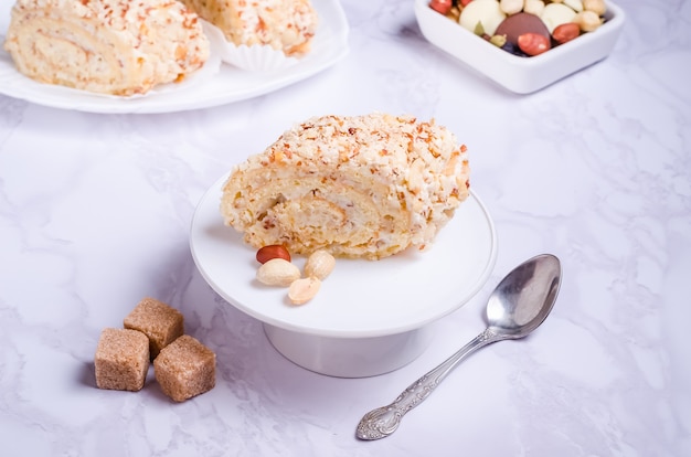 Cake roll with peanuts with cream on a white plate