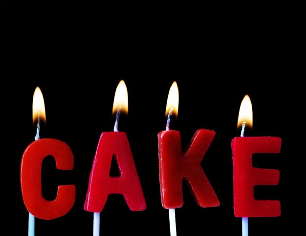 Cake spellt out in red birthday candles against a black background