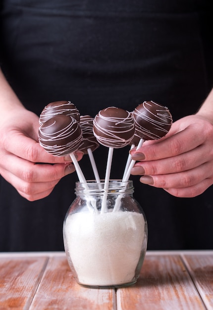 Cake springt in chocoladeroom in de vorm van een boeket staan in potten met suiker op een houten achtergrond.